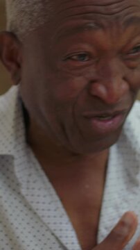 Elderly African American man sneezing outdoors, covering nose close up portrait