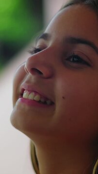 Joyful young girl with brown hair opening eyes and smiling outdoors, feeling happy