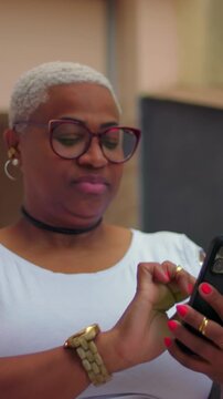 Neutral African American woman with glasses typing message on smartphone outdoors