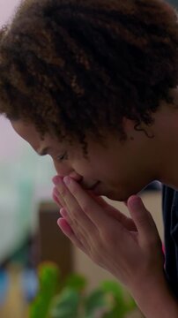 Overwhelmed Hispanic boy of African descent sitting with hands covering face outdoors