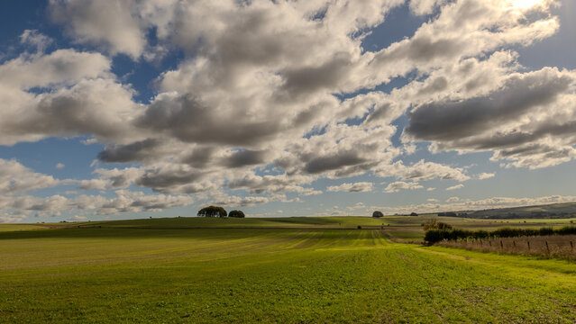 Marlborough Downs in Wiltshire, England. Soft rolling chalk landscape. Ideal for low level arable farming and sheep, goat and cattle grazing on the slopes. Dark menacing clouds formed over the fields.