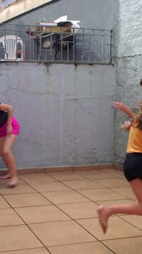Playful children chasing each other in courtyard tag game, energetic family fun