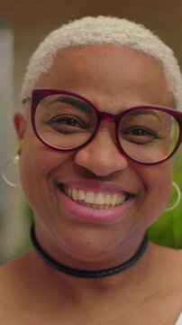 Smiling African American woman with glasses close up portrait outdoors, joyful