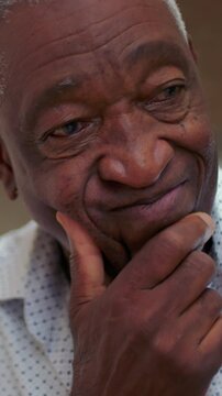 Thoughtful elderly African American man resting chin on hand indoors, introspective senior portrait