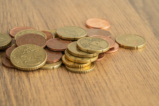 Euro coins scattered and stacked on a wooden table during daytime