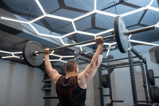 A muscular man lifts a barbell.