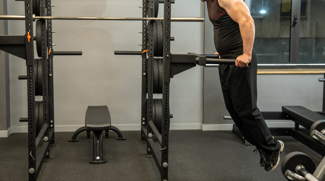 A male athlete performs parallel bar dips in the gym.