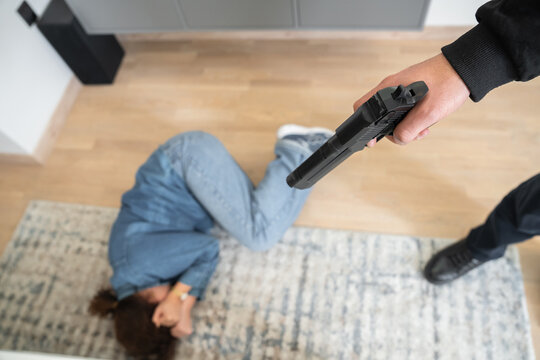 A guy shoots a girl, and the girl covers herself with her hands.