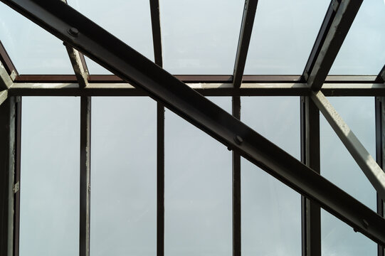 Low angle view of metal and glass roof frame with bolts