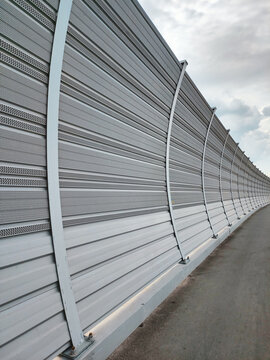 Perspective view of metal sound barrier wall along road