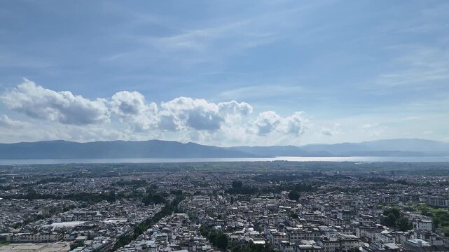 Aerial view of a plateau city with a large lake on the horizon and white clouds in blue sky, Southwest China, D-Log lossless file format
