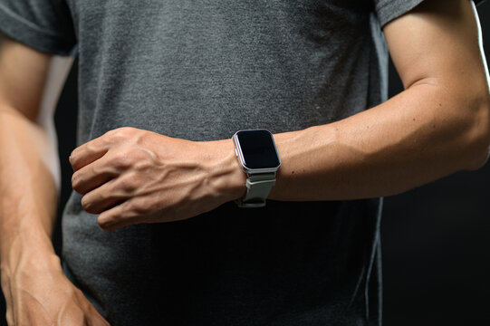 Close-up of a person wearing a smartwatch on wrist against dark background