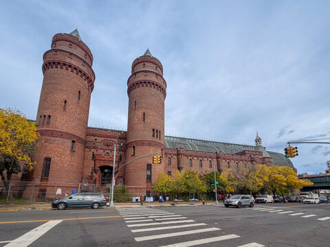 Bronx, NY - US - Oct 17, 2026 : The Kingsbridge Armory stretches along Jerome Avenue with twin brick towers, a broad curved roof and crenellated walls, while cars and pedestrians. The sky is overcast.