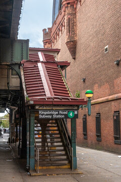 Bronx, NY - US - Oct 17, 2026 : The long red brick side wall of the Kingsbridge Armory stands beside the elevated railway and a stairway to the Kingsbridge. The scene is outdoors. The sky is overcast.