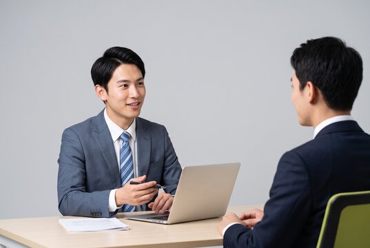 スーツ姿の男性が向かい合って打ち合わせをする様子、面接や採用、ビジネス相談のイメージ