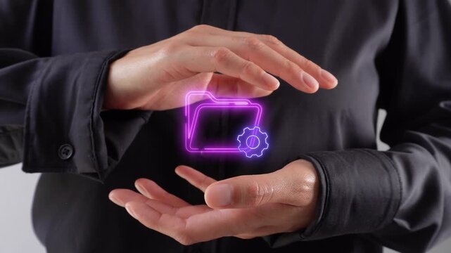 File management. A close-up of a woman&rsquo;s hands cupping a virtual icon representing a folder and a gear.