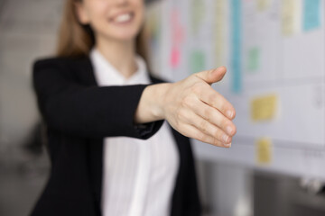 Close up young businesswoman in formal suit extending hand for handshake offering agreement partnership professional collaboration welcoming new client inviting or greeting partner with trust respect © fizkes