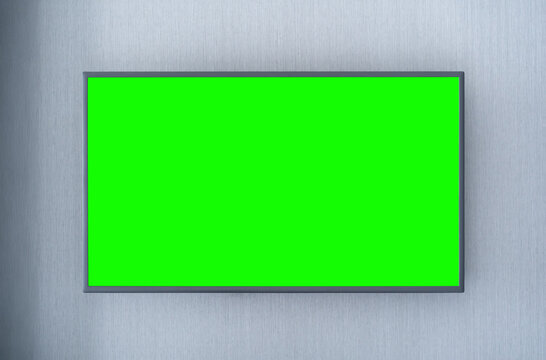 empty wide screen led television or wall mounted tv with blank green space display and black frame for monitor hanging on gray background in room for entertainment isolated included clipping path