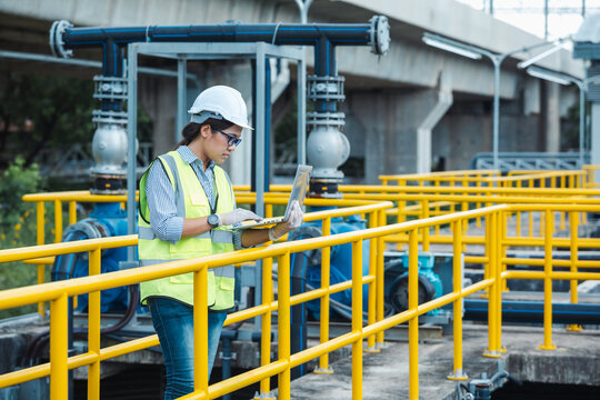 Young female engineer checks wastewater quality with laptop as part of industrial environment concept project.  Engineering inspection, environmental management.