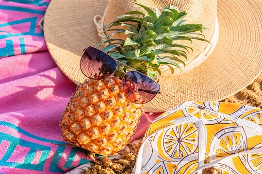 Stylish Pineapple Wearing Sunglasses on Colorful Beach Towels with Straw Hat &ndash; Tropical Summer Vacation Concept