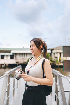Solo female traveler enjoy travel local river settlement community using digital camera taking photo