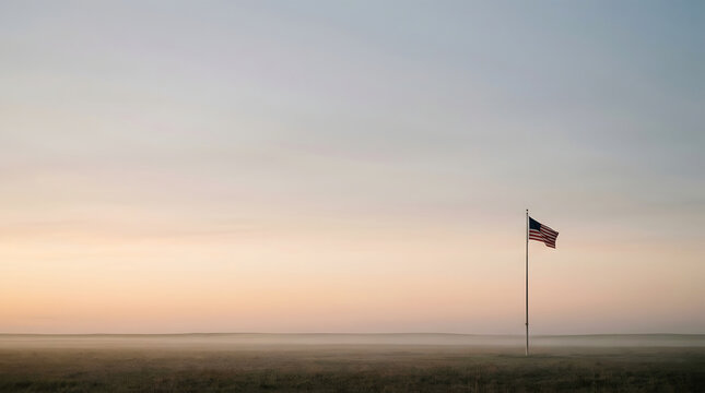 American flag waving gently in a field during a peaceful sunrise or sunset