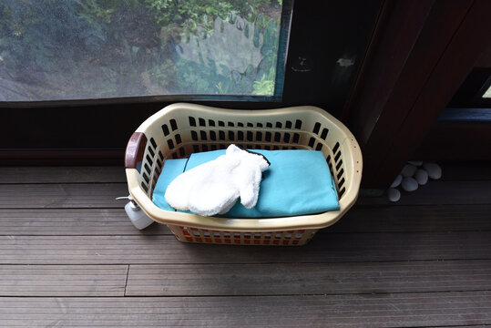 Laundry basket with folded towels and soap dispenser on a wooden deck