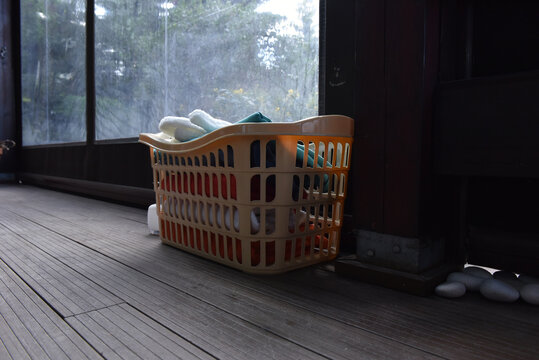 Laundry basket with folded towels and soap dispenser on a wooden deck