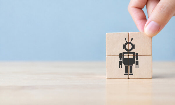 Robot concept. Technological revolution. Digital disruption. Symbol of future cooperation, technology advance, innovation. Hand holds wooden cubes with robot symbol on blue background, copy space.