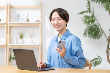 スマートフォンとパソコンを使う女性