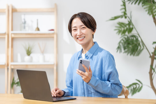 スマートフォンとパソコンを使う女性