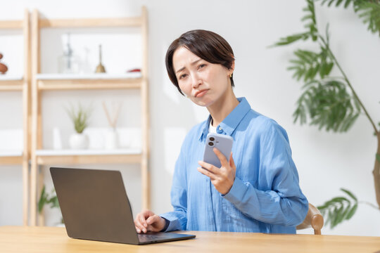 スマホを見て悩む女性