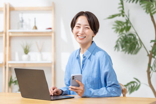 スマートフォンとパソコンを使う女性