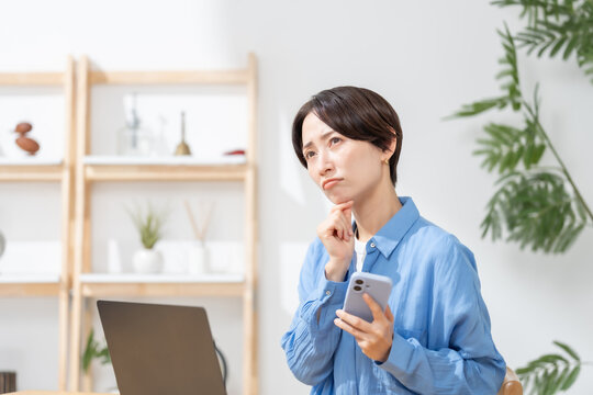 スマホを見て悩む女性