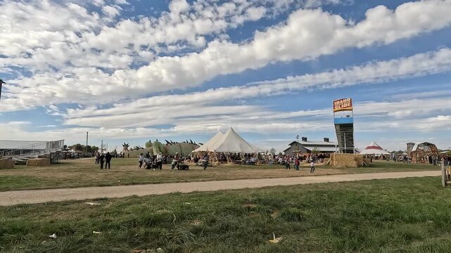 Wide landscape view of a festive autumn pumpkin patch farm with a tent and slide under a beautiful cloudy blue sky in Boise, Idaho