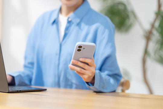 スマートフォンとパソコンを使う女性