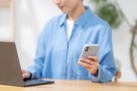 スマートフォンとパソコンを使う女性