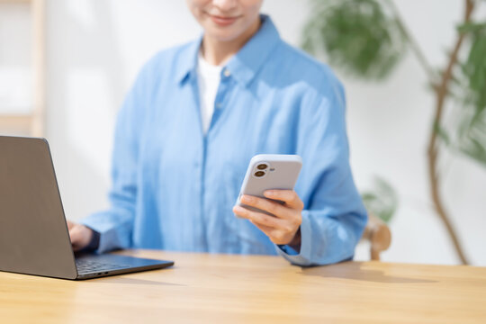 スマートフォンとパソコンを使う女性