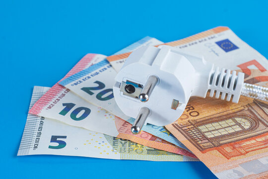 White power plug on euro banknotes over blue background. Electricity bill, rising energy costs, power expense and inflation concept.