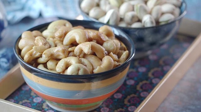 Bowls of cashews and pistachios arranged on a patterned table