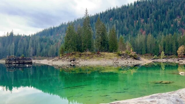 Autumn scenery at Lake Cauma in Flims, Switzerland, with its small island reflected in calm, mirror-like water beneath a cloudy sky, symbolizing tranquility, mindfulness and natural beauty.