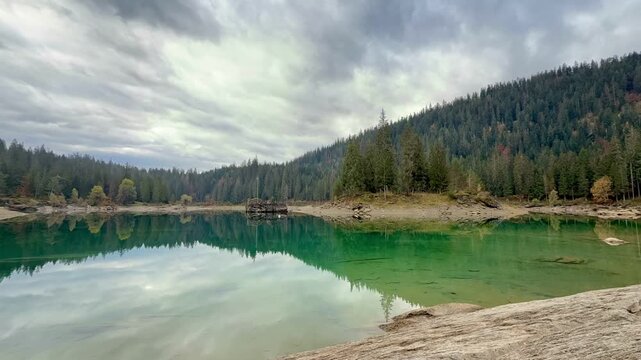 Autumn scenery at Lake Cauma in Flims, Switzerland, with its small island reflected in calm, mirror-like water beneath a cloudy sky, symbolizing tranquility, mindfulness and natural beauty.