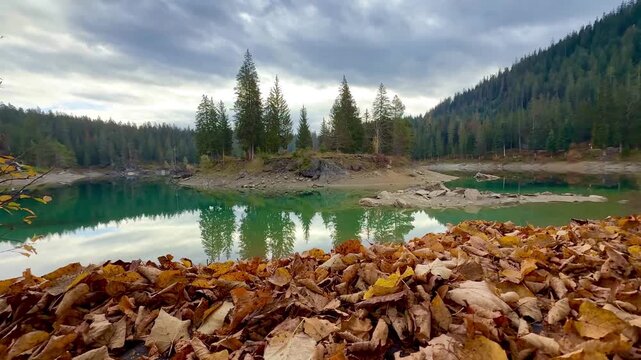 Autumn scenery at Lake Cauma in Flims, Switzerland, with its small island reflected in calm, mirror-like water beneath a cloudy sky, symbolizing tranquility, mindfulness and natural beauty.