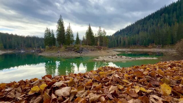 Autumn scenery at Lake Cauma in Flims, Switzerland, with its small island reflected in calm, mirror-like water beneath a cloudy sky, symbolizing tranquility, mindfulness and natural beauty.