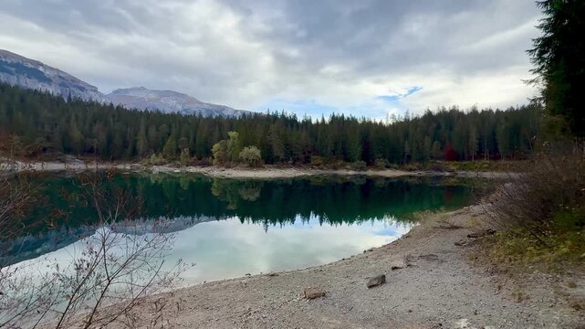 Autumn scenery at Lake Cauma in Flims, Switzerland, with its small island reflected in calm, mirror-like water beneath a cloudy sky, symbolizing tranquility, mindfulness and natural beauty.
