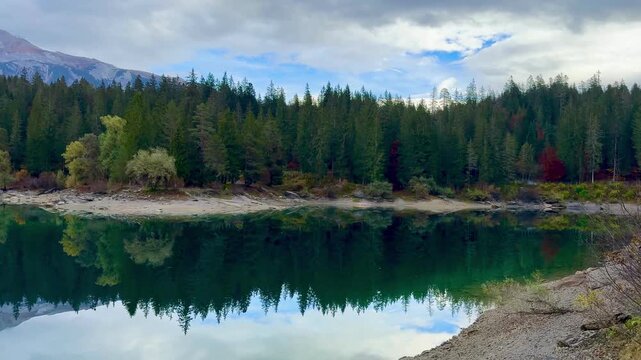 Autumn scenery at Lake Cauma in Flims, Switzerland, with its small island reflected in calm, mirror-like water beneath a cloudy sky, symbolizing tranquility, mindfulness and natural beauty.
