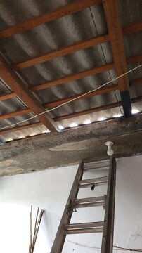 Aluminum Ladder Leaning Against Wall and Metal Roof