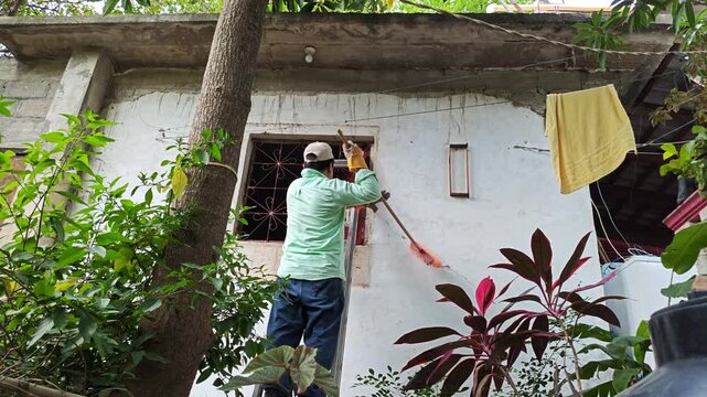 Young Person Sweeping Exterior Window Frame with Broom
