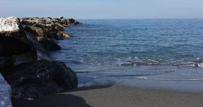 Stone breakwater rocks sea waves Sestri Levante sandy beach coast. Marine geology coastal protection calm blue water horizon. Oceanography natural science earth conservation publishing.