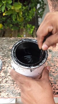 Hand Stirring Black Paint Can with Mixing Stick